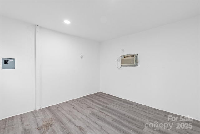 spare room featuring an AC wall unit and light hardwood / wood-style flooring