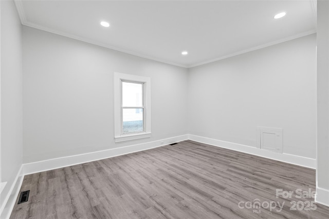 empty room with crown molding and light wood-type flooring