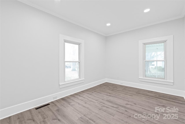 spare room with ornamental molding, plenty of natural light, and wood-type flooring