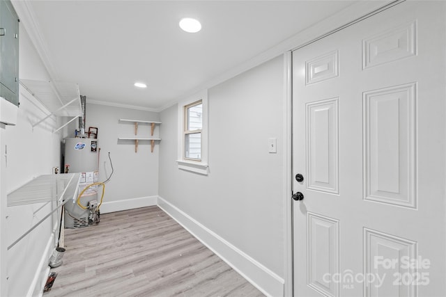 laundry area featuring gas water heater, ornamental molding, and light wood-type flooring