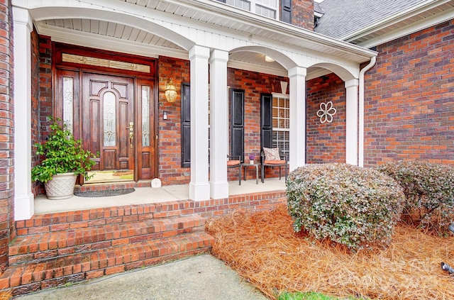 entrance to property with brick siding and a porch