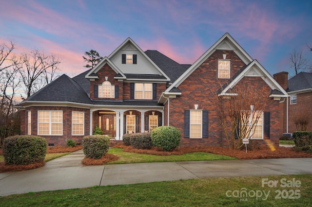 traditional-style house featuring crawl space, a shingled roof, a porch, and brick siding