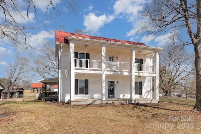 view of front of home with a balcony, metal roof, a front lawn, and a porch