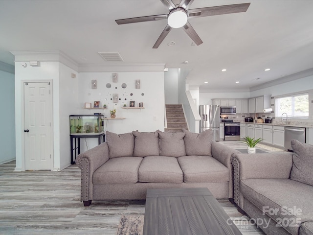 living room with crown molding, sink, ceiling fan, and light hardwood / wood-style flooring