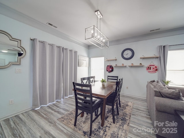 dining space featuring a wealth of natural light, ornamental molding, and light hardwood / wood-style floors