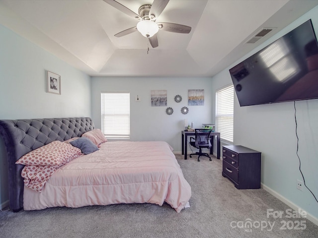 carpeted bedroom featuring a raised ceiling and ceiling fan