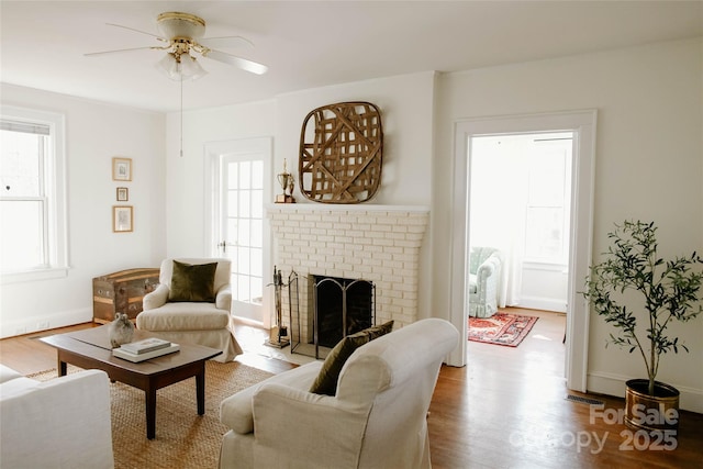 living area with wood finished floors, visible vents, a ceiling fan, baseboards, and a brick fireplace