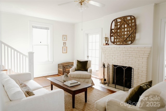 living area with ceiling fan, a fireplace, and wood finished floors