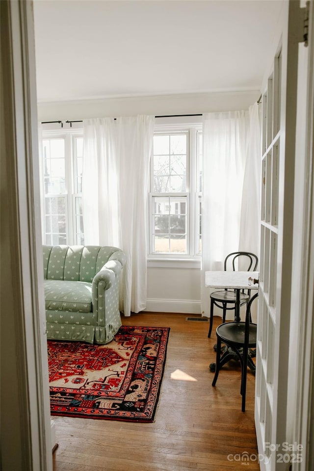 living area featuring wood finished floors, visible vents, and baseboards