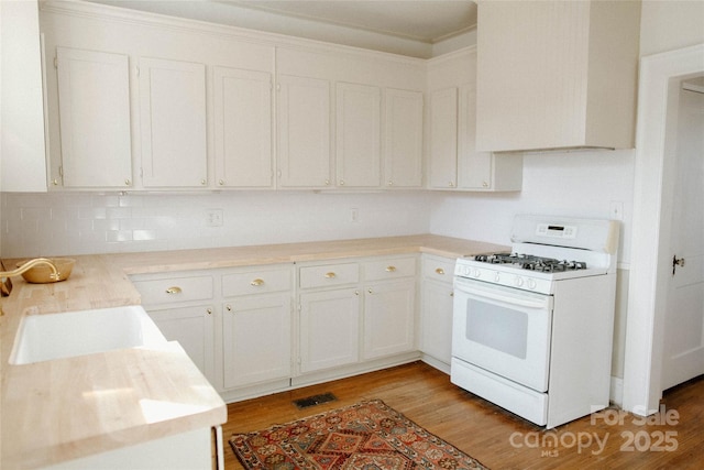 kitchen featuring light wood-style flooring, white range with gas stovetop, white cabinetry, and light countertops