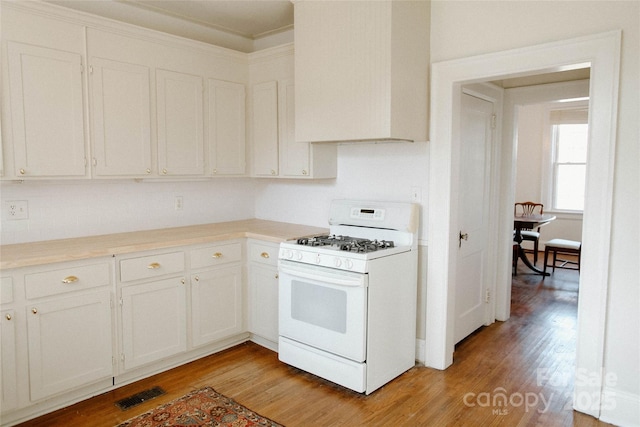 kitchen with light wood-type flooring, white gas range, visible vents, and white cabinets