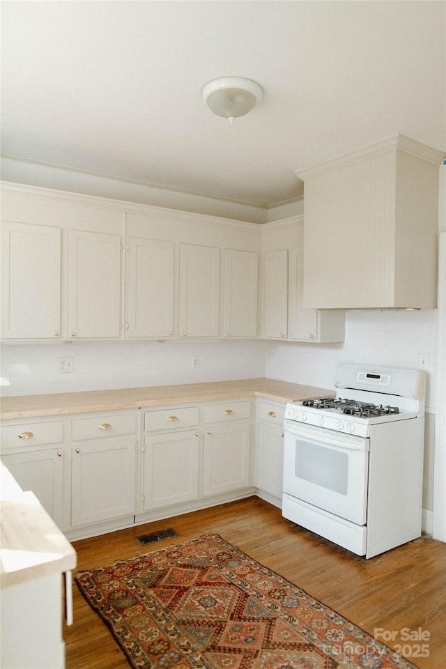 kitchen with light countertops, visible vents, white cabinetry, light wood-type flooring, and white gas range oven