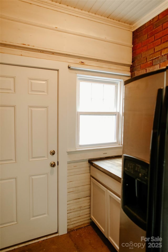 kitchen with refrigerator with ice dispenser and brick wall