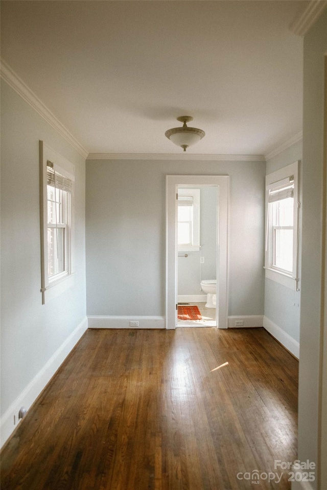 spare room with a healthy amount of sunlight, ornamental molding, and wood finished floors