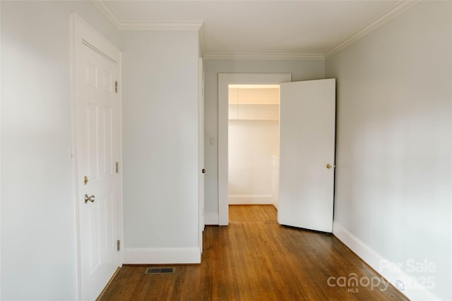 unfurnished bedroom featuring visible vents, crown molding, baseboards, and wood finished floors