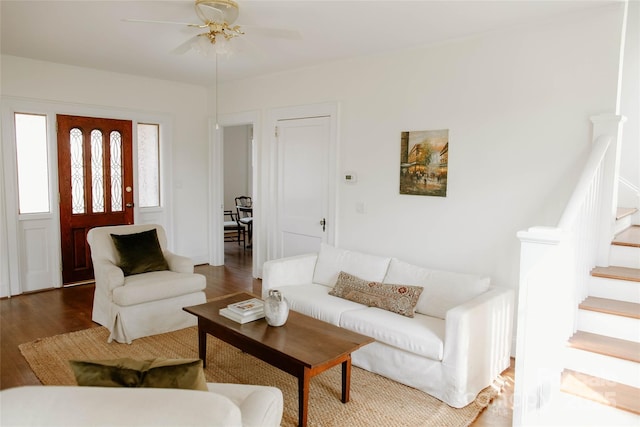 living area with a ceiling fan, stairway, and wood finished floors