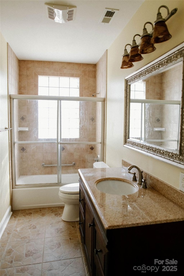 bathroom featuring toilet, visible vents, combined bath / shower with glass door, and vanity