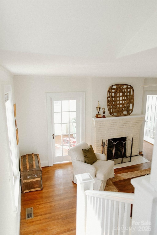 living area with light wood finished floors, a fireplace, and visible vents