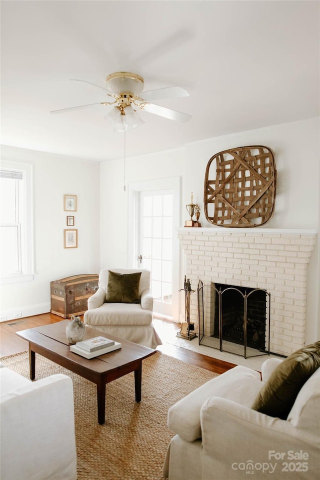 living area with plenty of natural light, wood finished floors, and a brick fireplace