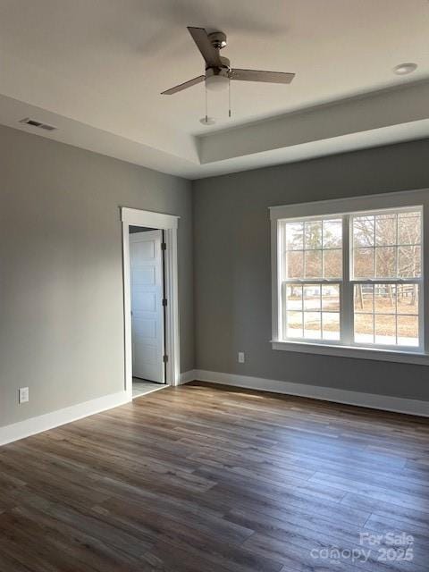 empty room with hardwood / wood-style flooring, ceiling fan, and a tray ceiling