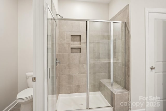 bathroom featuring a shower with shower door and toilet