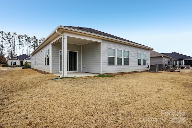 rear view of property with central AC unit, a patio area, and a lawn