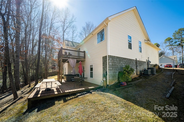 rear view of house with central AC unit, a balcony, a jacuzzi, a deck, and a yard