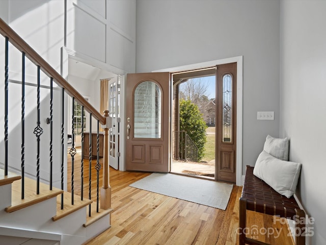 entrance foyer with stairs, wood finished floors, and a towering ceiling