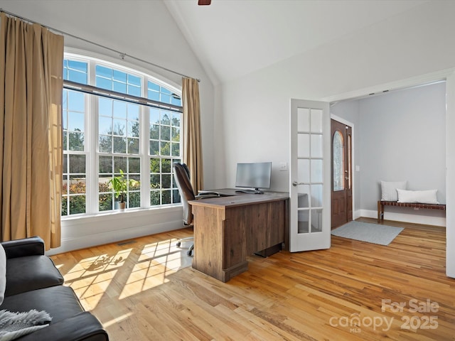 office area with light wood-style floors, high vaulted ceiling, and french doors