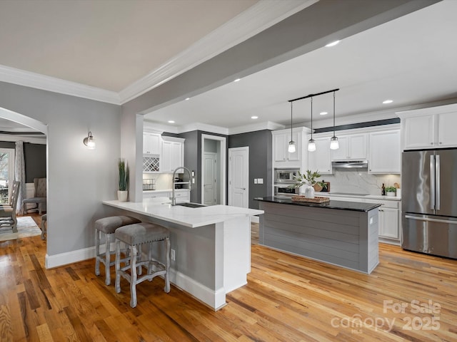 kitchen with a peninsula, a sink, white cabinets, appliances with stainless steel finishes, and backsplash