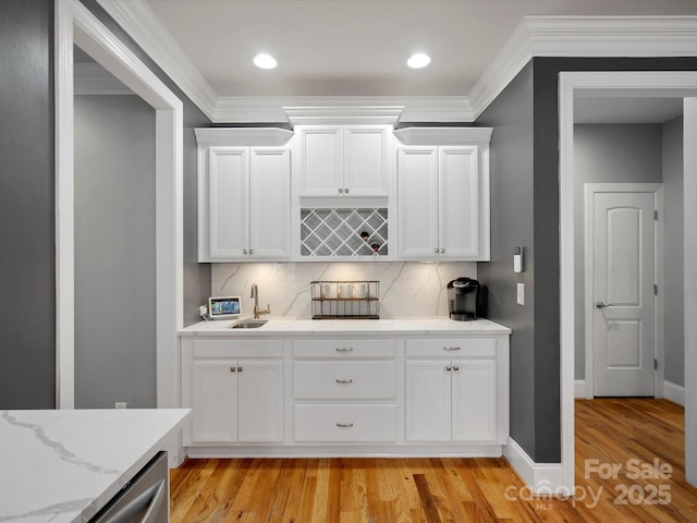 kitchen featuring crown molding, light wood-style floors, a sink, and white cabinets