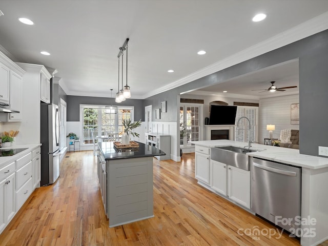 kitchen featuring a center island, stainless steel appliances, a fireplace, white cabinetry, and a sink