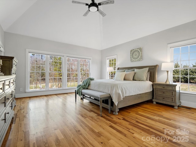 bedroom with light wood-style floors, multiple windows, and high vaulted ceiling