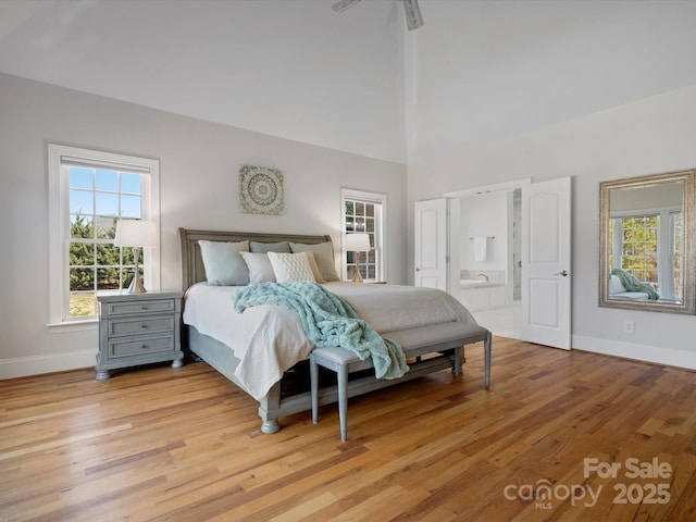 bedroom with baseboards, a high ceiling, and light wood-style floors