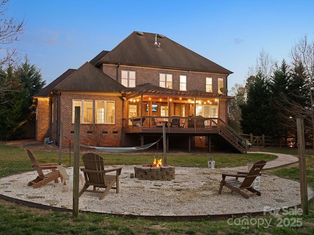 rear view of house with a deck, an outdoor fire pit, brick siding, stairs, and crawl space