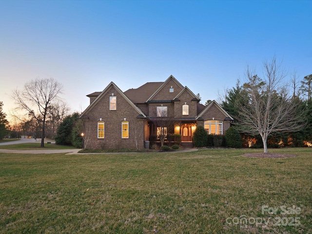 view of front of house featuring brick siding, a lawn, and a porch