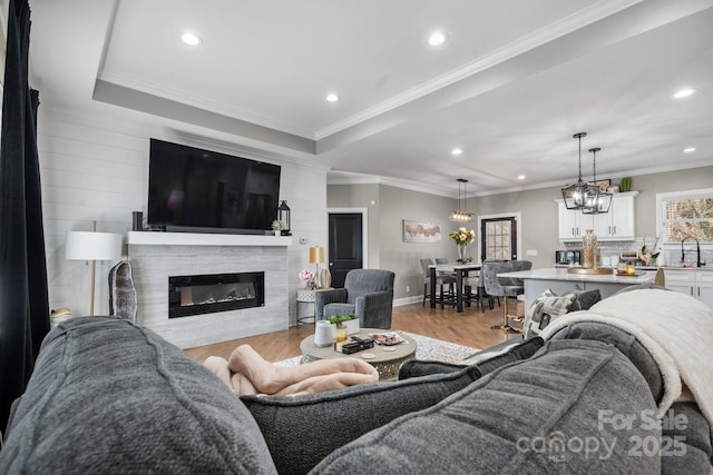 living room with crown molding, sink, a wealth of natural light, and light hardwood / wood-style floors