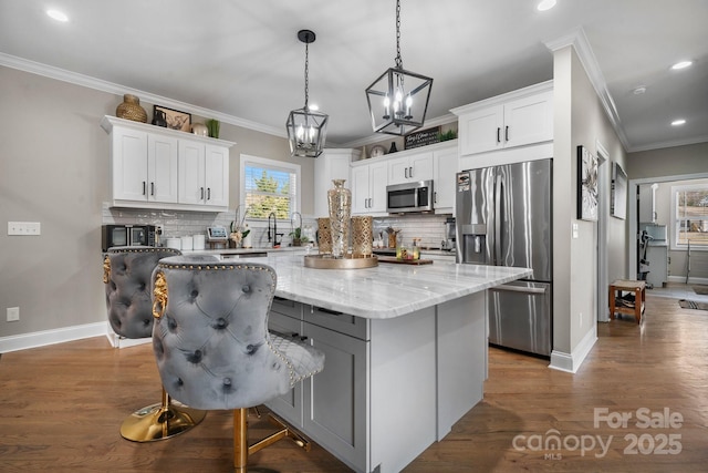 kitchen featuring stainless steel appliances, light stone countertops, a kitchen island, and white cabinets