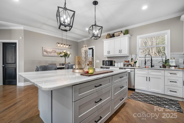 kitchen featuring sink, a center island, hanging light fixtures, stainless steel dishwasher, and white cabinets