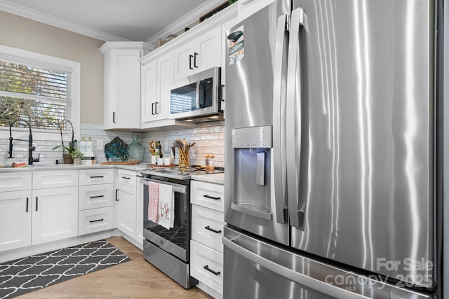 kitchen featuring sink, white cabinetry, crown molding, appliances with stainless steel finishes, and backsplash