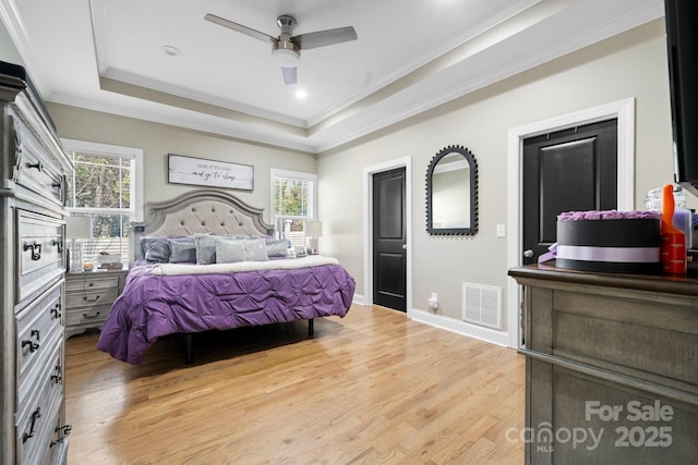 bedroom featuring ceiling fan, ornamental molding, a raised ceiling, and light wood-type flooring