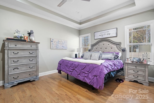 bedroom featuring a tray ceiling, ornamental molding, ceiling fan, and light wood-type flooring