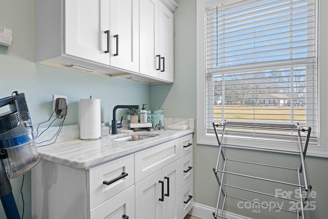 interior space with sink, white cabinets, and light stone counters