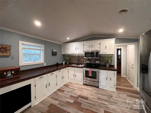 kitchen with white cabinetry, backsplash, stainless steel appliances, and lofted ceiling