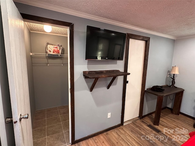 hallway with ornamental molding, wood-type flooring, and a textured ceiling