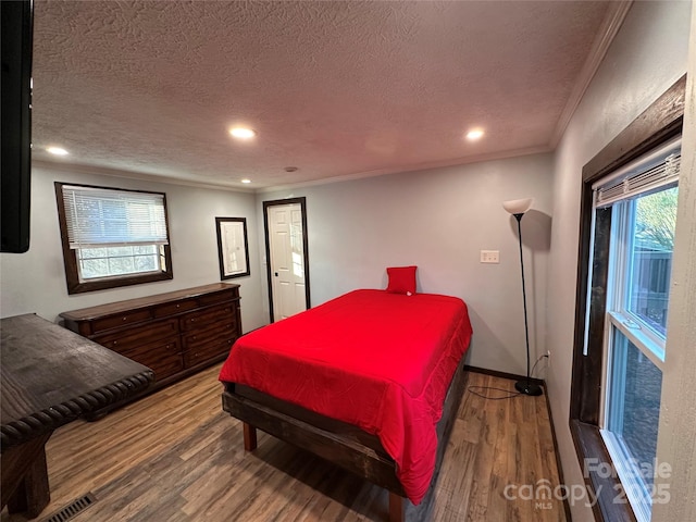 bedroom featuring hardwood / wood-style flooring, ornamental molding, and a textured ceiling