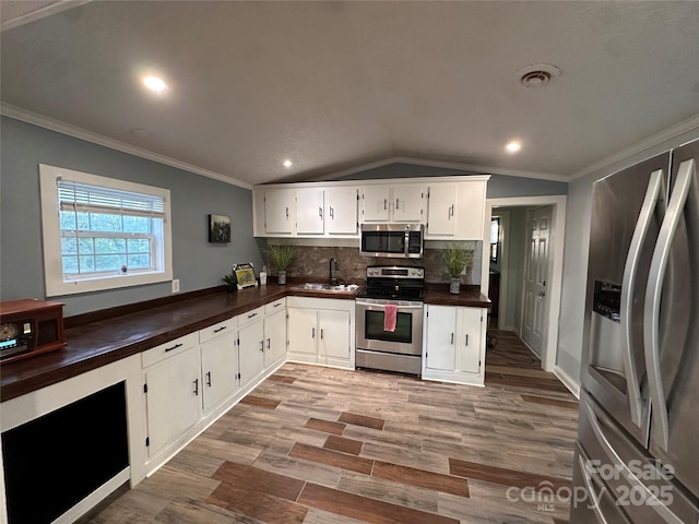 kitchen with lofted ceiling, sink, stainless steel appliances, decorative backsplash, and white cabinets