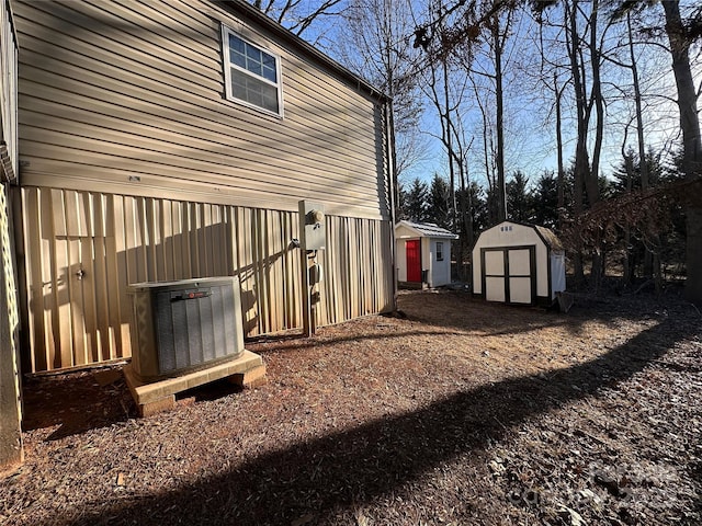 view of side of home featuring cooling unit and a storage shed