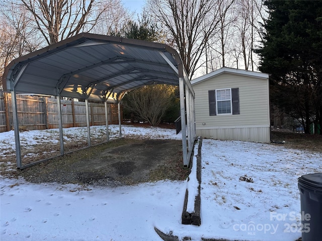 snow covered parking area with a carport