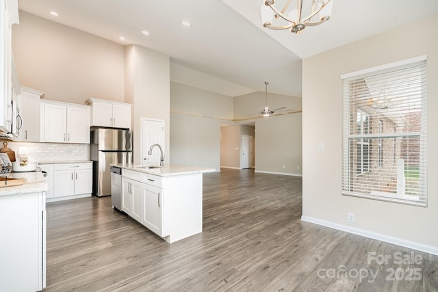 kitchen with sink, stainless steel appliances, light stone countertops, light hardwood / wood-style floors, and white cabinets